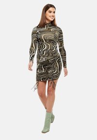 Form-fitting dress in abstract brown and black swirl pattern. Features long sleeves, gathered sides, and adjustable drawstrings at the hem.
