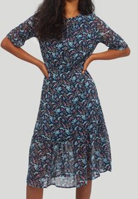 Granatowa sukienka w kwiaty z krótkimi rękawami, zebranym w pasie i wielowarstwowym falbanym dołem. Cechuje się mieszanką niebieskich i różowych wzorów kwiatowych.