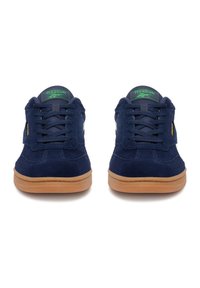 Marineblaue Wildledersneaker mit einer Gummisohle in Braun, ausgestattet mit Schnürverschluss, Reebok-Logo auf der Zunge und hellen Akzenten an den Seiten.