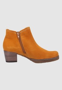 Bottines en daim jaune avec une fermeture éclair latérale, un bout arrondi et un talon empilé en bois. Des détails de surpiqûres contrastées mettent en valeur le design.