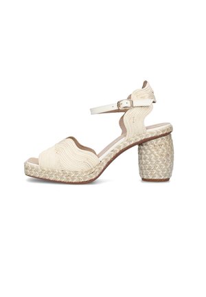 Sandalo beige da donna con tacco a blocco intrecciato, cinturini con motivo a onde e chiusura con fibbia alla caviglia, mostrato su sfondo bianco.