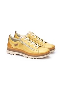Zapatillas de cuero amarillas con un acabado texturizado, que cuentan con una cremallera lateral, cordones en contraste y un diseño de suela robusta.