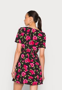 Vestido floral com fundo preto e flores de hibisco rosa. Mangas curtas, cintura ajustada e comprimento acima dos joelhos. Textura suave.