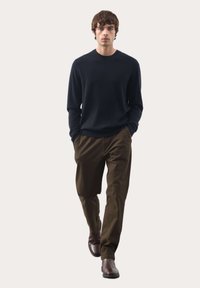 Maglione navy a girocollo, pantaloni marroni e stivali marroni. Il tessuto appare liscio, con un design aderente e una silhouette casual.