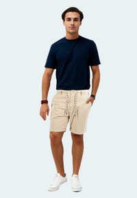 Navy crew-neck t-shirt, beige shorts with drawstring and rolled hems, paired with white sneakers. Simple, casual outfit design.