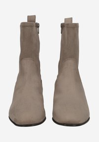 Bottines en daim beige avec un bout pointu, des fermetures éclair sur les côtés et des tirettes à l'arrière. Texture lisse et design minimaliste.