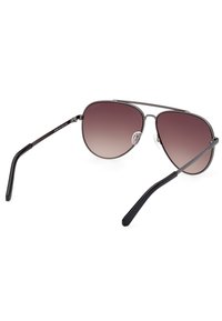 Ochelari de soare metalici tip aviator cu lentile degradate de la mov la gri, brațe subțiri negre și suporturi pentru nas transparente. Design elegant al ramei cu accente minime.