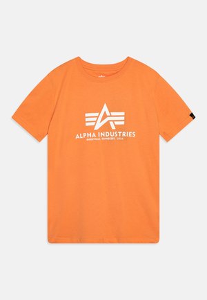 T-shirt orange à manches courtes avec logo blanc Alpha Industries et texte "Knoxville, Tennessee, U.S.A." à l'avant sur fond uni.