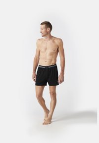 Zwarte boxershorts met een Smartwool-logo op de tailleband, gemaakt van zachte stof, met een relaxte pasvorm en een lengte tot halverwege de dij.