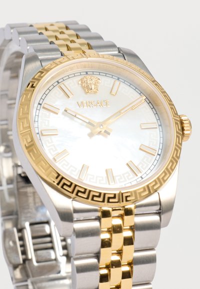Πολυτελές ρολόι χειρός Versace με χρυσό και ασημένιο μπρασελέ, λευκό καντράν, χρυσούς δείκτες ώρας, δείκτες και λογότυπο Μέδουσα στη θέση 12 η ώρα.