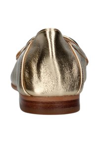 Mocassini metallici dorati con una superficie liscia, punta arrotondata e un tacco in legno basso. Presentano un accento cucito lungo la parte superiore.