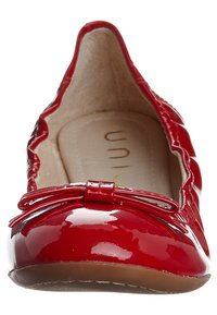 Ballerines en cuir verni rouge avec un bout arrondi, ornées d'un accent en forme de nœud à l'avant. L'intérieur est beige, affichant une texture lisse.
