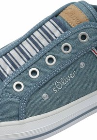 Sinine teksast sneaker, millel on hõbedased silmad, triibulised kangast aktsendid ja helepruun nahkpatch, millel on külje peal reljeefne "s.Oliver".