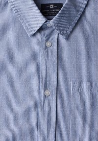 Hemd mit Knöpfen in blau-weiß gestreiftem Muster, ausgestattet mit einer Brusttasche, aus weichem Stoff und mit rundem Kragen sowie grauen Knöpfen.