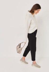 Biely kapucňový sveter s dlhými rukávmi, čierne priliehajúce nohavice a svetlošedé šľapky. Doplnkový k béžovej kabelke so vzorom hada.