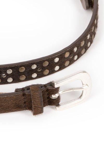 Bruine leren riem met haar, voorzien van zilveren studs, een zilveren metalen gesp en een gestructureerd oppervlak, bevestigd met een leren keeper.