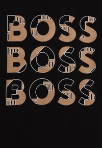 Juodas audinys, ant kurio žodį "BOSS" kartojasi didelėmis raidėmis. Raidės yra su solidžiu kreminės ir baltos spalvos kontūru bei geometriniais akcentais.