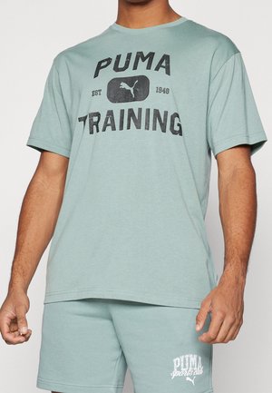 Mann trägt ein hellgrünes Puma Trainings-T-Shirt und passende Puma Sports Club Shorts, beschnitten an Schultern und Knien.
