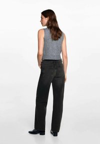 Sivý top bez rukávov v kombinácii s tmavosivými riflami s vysokým pásom. Rifle majú rovný strih a zadné vrecká, s hladkou štruktúrou.