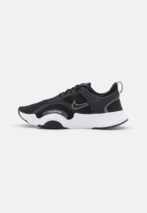 Zapatilla deportiva Nike en blanco y negro con parte superior de malla, cierre de cordones, suela curva y marca "superrep" en el lateral.