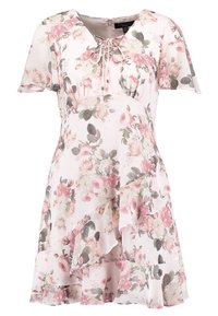 Robe fleurie en tissu rose doux, avec des manches courtes, un décolleté en V avec un détail de lien, un ourlet froncé, et divers motifs de fleurs avec des feuilles vertes.