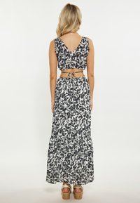 Set floral format din două piese, care include un top scurt cu spate în V și o fustă lungă cu tiv înclinat, din material alb și negru. Asortat cu sandale cu platformă.