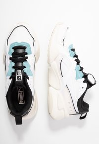 Scarpe da ginnastica bianche e nere con accenti azzurri, tomaia in mesh e materiale sintetico, collo imbottito e suola chunky beige.