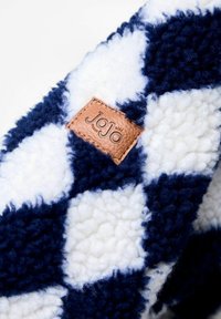 Tumši zila un balta pārbaudīta tekstila ar mīkstu, pūkainu tekstūru. Iekļauts brūns ādas uzlīme ar "JoJo bébé" zīmolu.