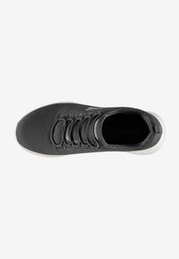 Zapato atlético negro con parte superior de malla, seis ojales, tejido texturizado, cuello acolchado y suela blanca. La vista superior resalta el sistema de cordones.