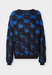 Maglione lavorato a maglia con una vestibilità ampia, caratterizzato da un corpo nero e un motivo astratto blu. Collo rotondo e maniche lunghe. Trama morbida.