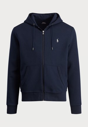 Mornarsko modra zip-up kapuca, narejena iz mehkega materiala, z nastavljivimi vrvicami, kenguru žepi, rebrastimi manšetami in majhnimlogotipom na prsih.