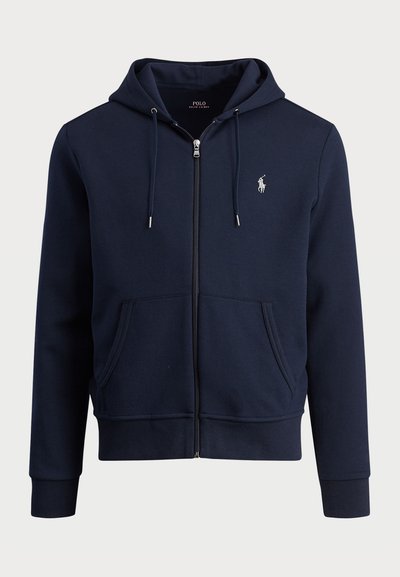 Sudadera con cremallera de color azul marino, hecha de tela suave, con cordones ajustables, bolsillos tipo canguro, puños acanalados y un pequeño logo en el pecho.