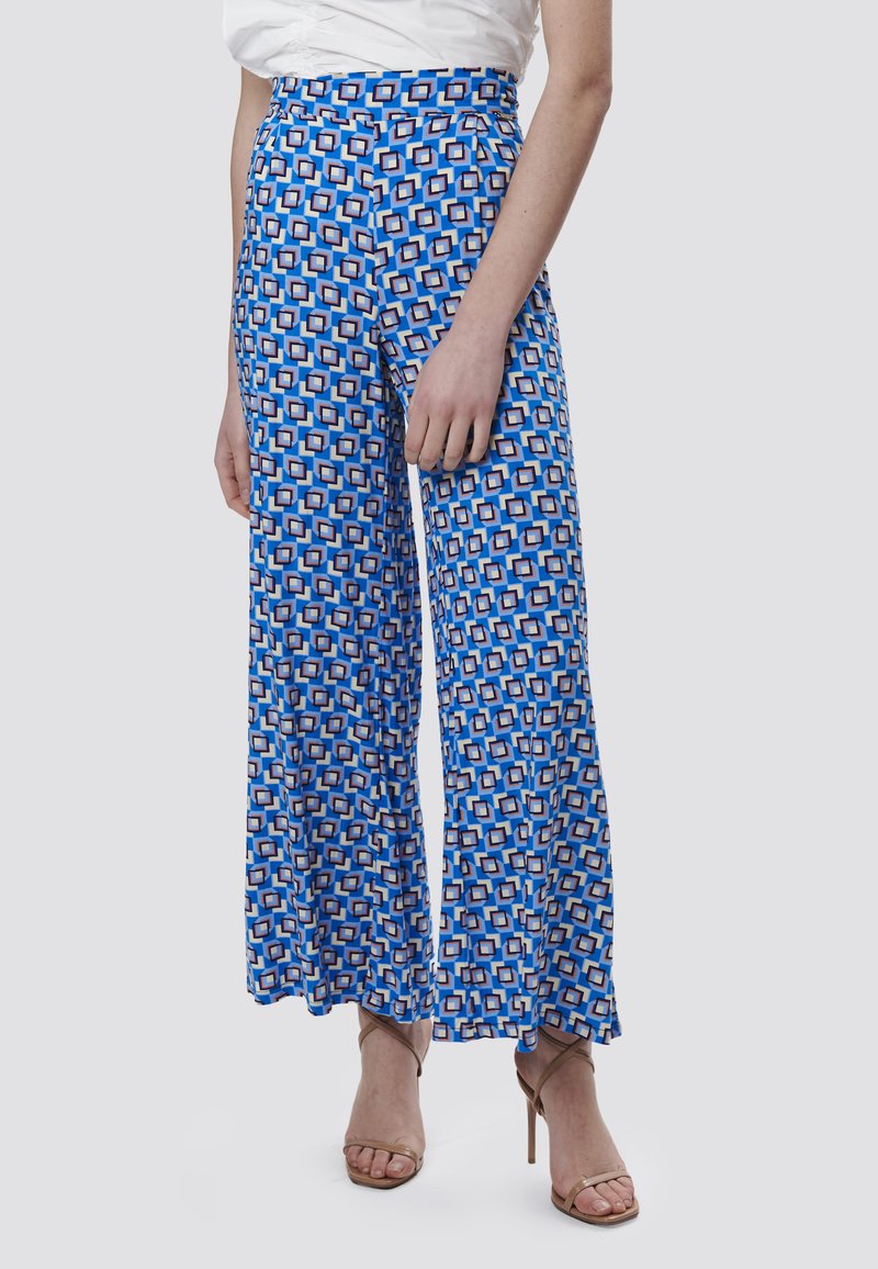 Blauwe wijde broek met een patroon van geometrische ontwerpen in wit en oranje, gemaakt van een lichtgewicht stof, met een hoge taille en een soepele textuur.