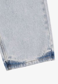 Jasnoniebieska tkanina dżinsowa z postrzępionym dołem, z kontrastującymi brązowymi szwami i lekko wyblakłym odcieniem ku dołowi.