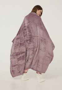 Coperta oversized viola con una texture morbida e peluche e una finitura liscia, caratterizzata da un sottile motivo astratto, che si drappeggia in modo elegante.