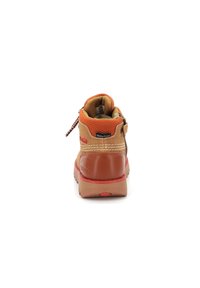 Bota impermeable de ante en tono marrón con acentos en naranja y detalles cosidos. Cuenta con un collar acolchado y una suela de goma con realces en rojo.