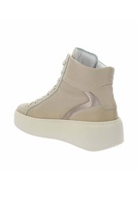 Zapatilla alta beige con suela blanca gruesa, parte delantera con cordones y acento metálico en el lado exterior, mostrada desde un ángulo trasero-derecho.