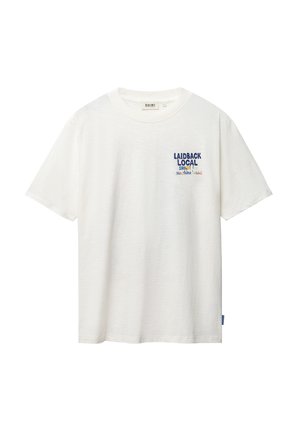 Camiseta blanca de manga corta con cuello redondo y pequeño texto "LAIDBACK LOCAL SHIWI sunshine" impreso en el pecho izquierdo.