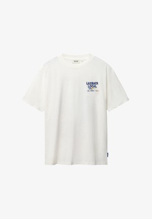 Camiseta blanca de manga corta con cuello redondo y pequeño texto "LAIDBACK LOCAL SHIWI sunshine" impreso en el pecho izquierdo.