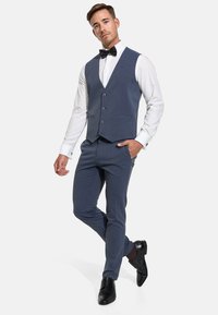 Gilet de costume bleu foncé avec pantalon assorti, chemise blanche et nœud papillon noir ; présente une texture lisse et cinq boutons, associé à des chaussures noires.