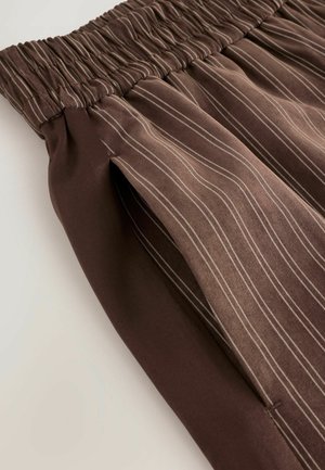 Brun plisseret nederdel med elastisk talje, prydet med lodrette striber i lysere nuancer. Glat tekstur, stoffet hænger blødt.