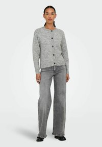 Grå stickad kofta med rund halsringning, knäppning och ribbade ärmar, kombinerad med högmidjade grå vida jeans och svarta stövlar.