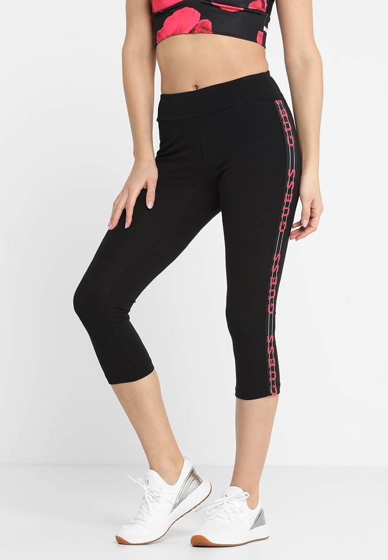 Leggings capri neri in tessuto elasticizzato con vita alta. Presentano dettagli con logo rosa sul lato e una texture liscia e elegante.