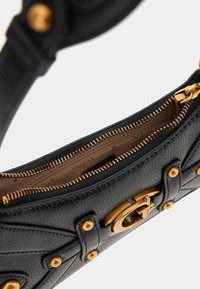 Sort lædertaske med guldfarvet hardware, udstyret med lynlås og nitter. Tekstureret overflade med en afgrænset form og synligt indvendigt foer.