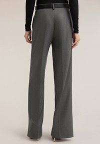 Grau maßgeschneiderte Hose mit glatter Textur, weitem Bein und zwei Gesäßtaschen. Verfügt über einen schwarzen Gürtel und gebügelte Bügelfalten für Struktur.