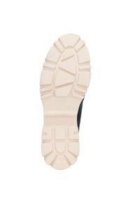 Suela de zapato con una suela externa de goma gruesa y texturizada en beige claro; presenta un patrón de relieve para agarre y estabilidad.