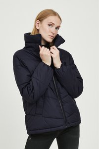 Veste matelassée bleu marine avec un col haut, dotée d'une fermeture éclair à l'avant et d'un design matelassé. Matériau léger avec des poignets élastiques.