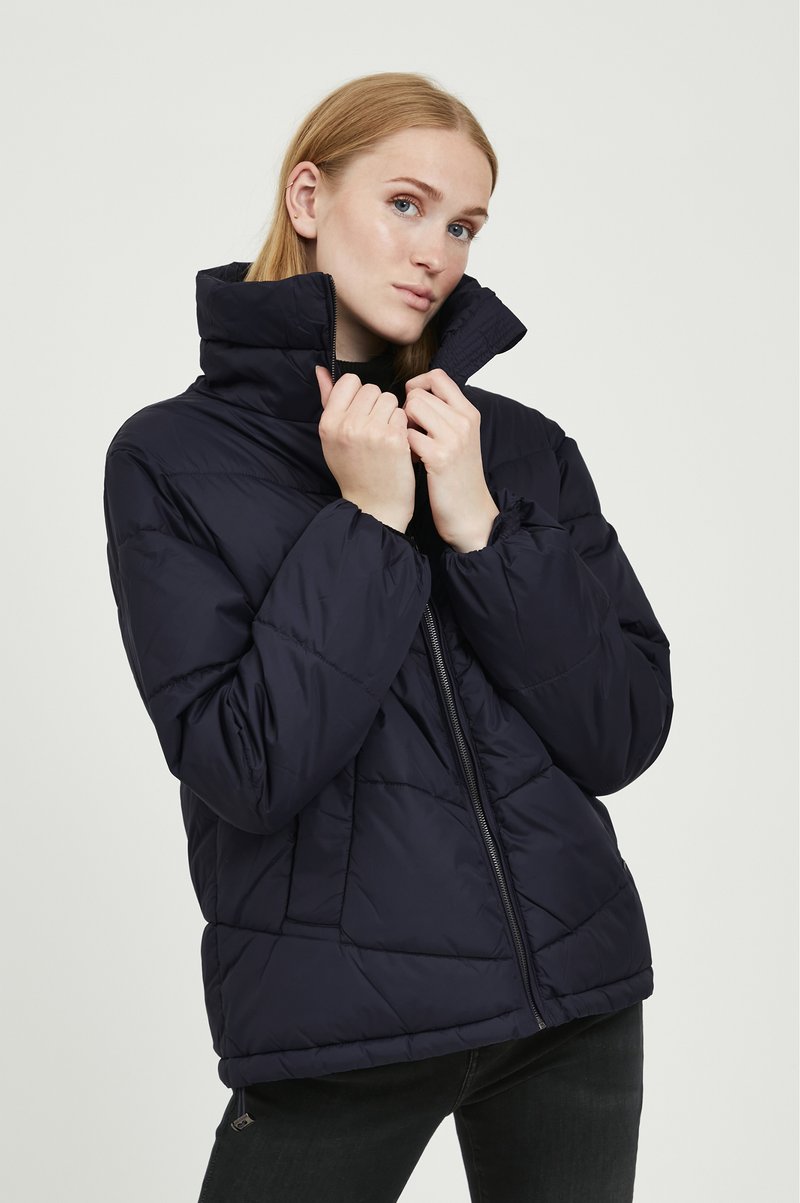 Veste matelassée bleu marine avec un col haut, dotée d'une fermeture éclair à l'avant et d'un design matelassé. Matériau léger avec des poignets élastiques.