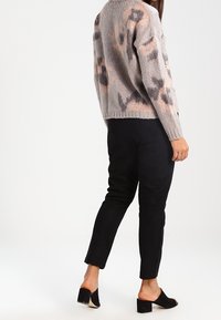 Pullover a maglia con motivo leopardato in tonalità grigie e rosa cipria, abbinato a pantaloni neri su misura e mule aperti neri con tacco a blocco.