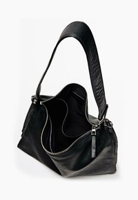 Sac à main en cuir noir avec une seule sangle, doté d'une fermeture éclair, de plusieurs compartiments et d'une texture lisse. L'intérieur est en tissu sombre.